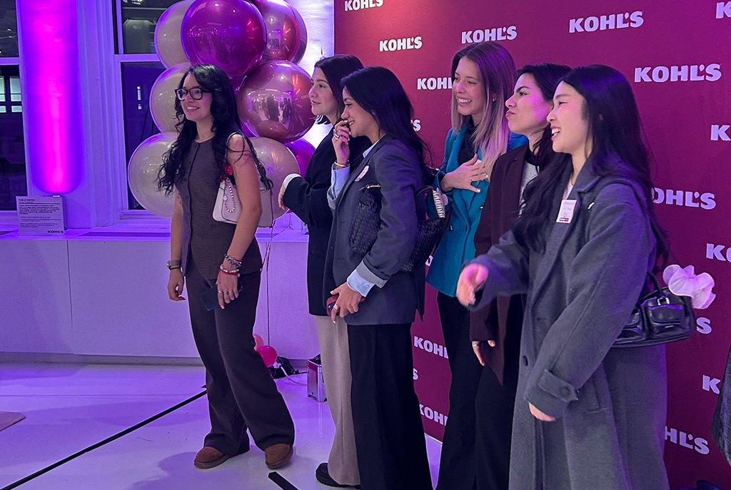 Students smiling while gathered in front of a step-and-repeat that reads Kohls