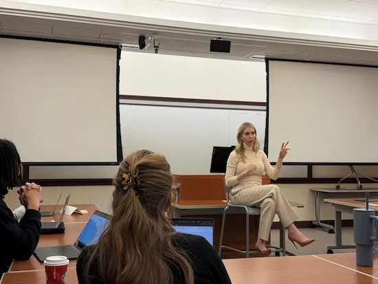 Andrea Albright sits on a stool in front of a Georgetown McDonough class